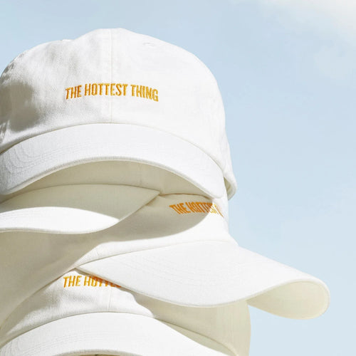 Close up shot of the Badalada Baseball hat. The text on the hat reads "the hottest thing" in yellow text with white hat