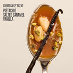 A spoonful of Pistachio Salted Caramel Vanilla scent from Cheirosa 62° Scent, featuring a glossy amber-brown syrup with pistachio pieces, a vanilla bean, and coarse salt, set against a light beige background with dark gray text.