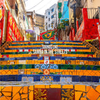 Colorful tiled staircase with a Brazilian flag and text 'Sounds Like Samba in the Streets' in an urban setting.