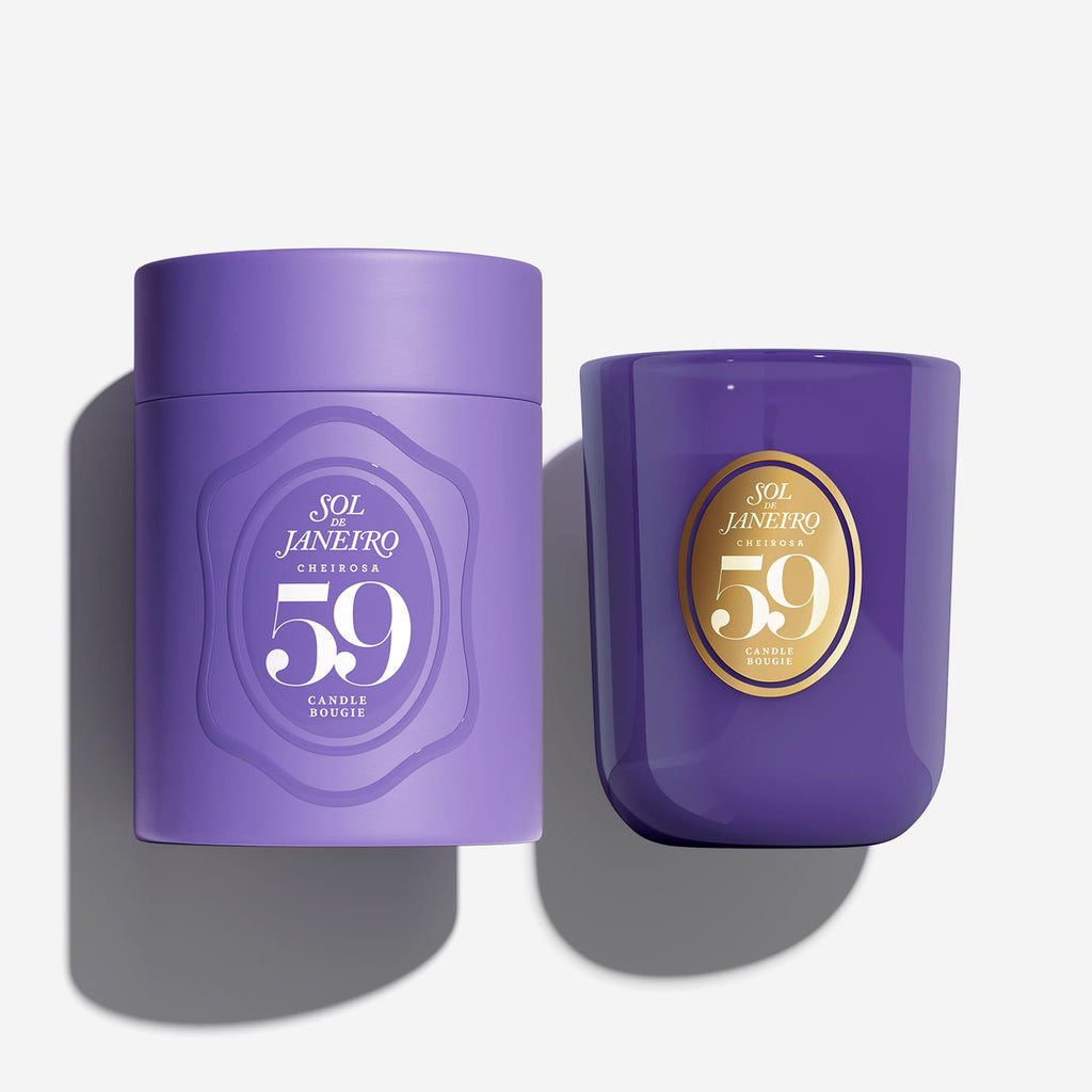 Two purple candle containers from Sol Janeiro Candle Co. on a light gray background, one matte purple cylinder with a purple lid and one glossy purple glass jar with a gold circular label.
