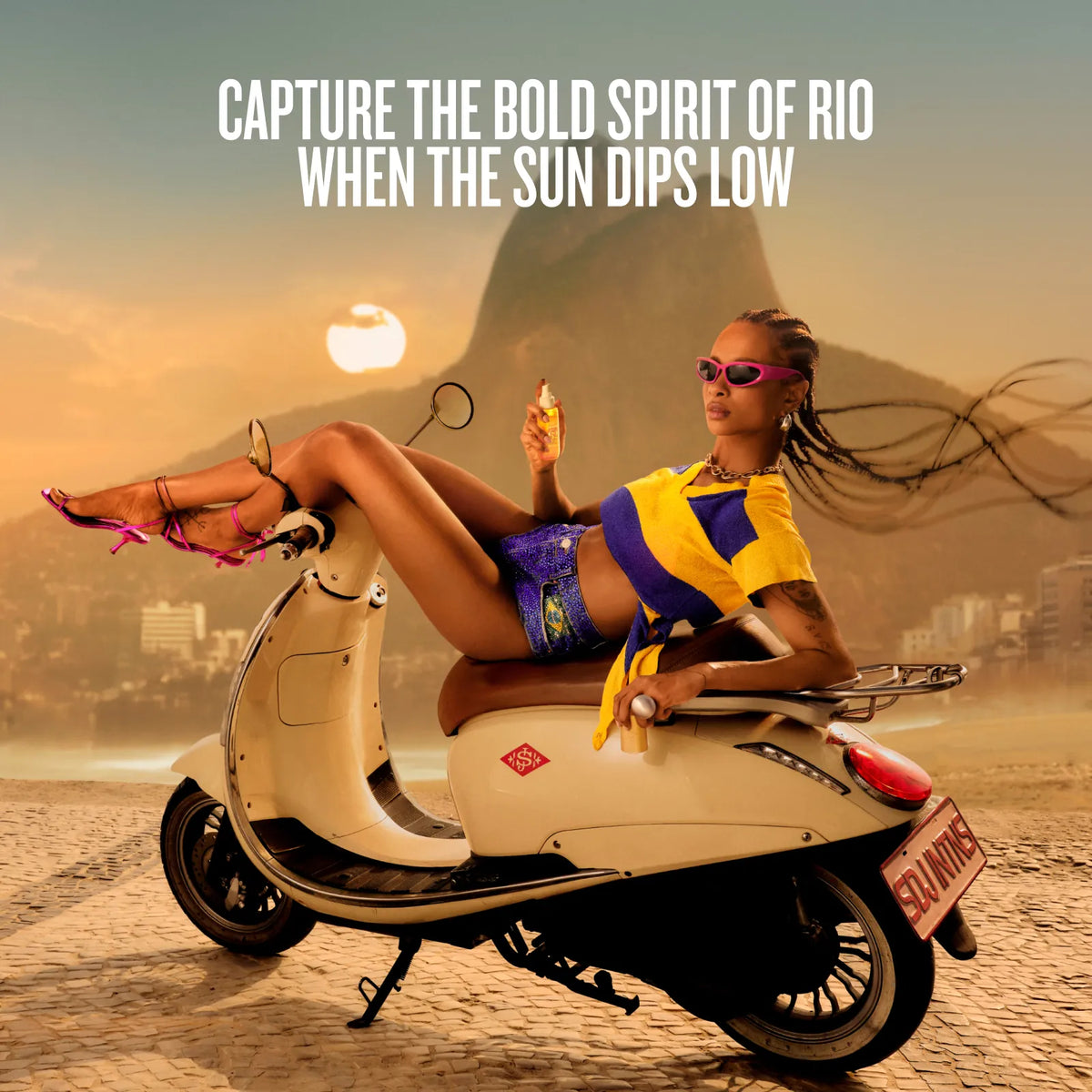 A woman reclining on a cream-colored scooter on a beach with a warm sunset sky, large text at the top reading 'CAPTURE THE BOLD SPIRIT OF RIO WHEN THE SUN DIPS LOW', and a Rio de Janeiro mountain backdrop.