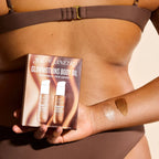 Person holding Sol de Janeiro Glowmotions Body Oil packaging with visible oil on arm