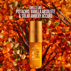 Sol Janeiro Intense 62 moisturizer bottle in a warm golden-amber color, centered against a textured background of amber glass pieces, vanilla beans, and pumpkin seeds. White text at the top reads: 'SMELLS LIKE PISTACHIO, VANILLA ABSOLUTE & SOLAR AMBERY ACCORD'.