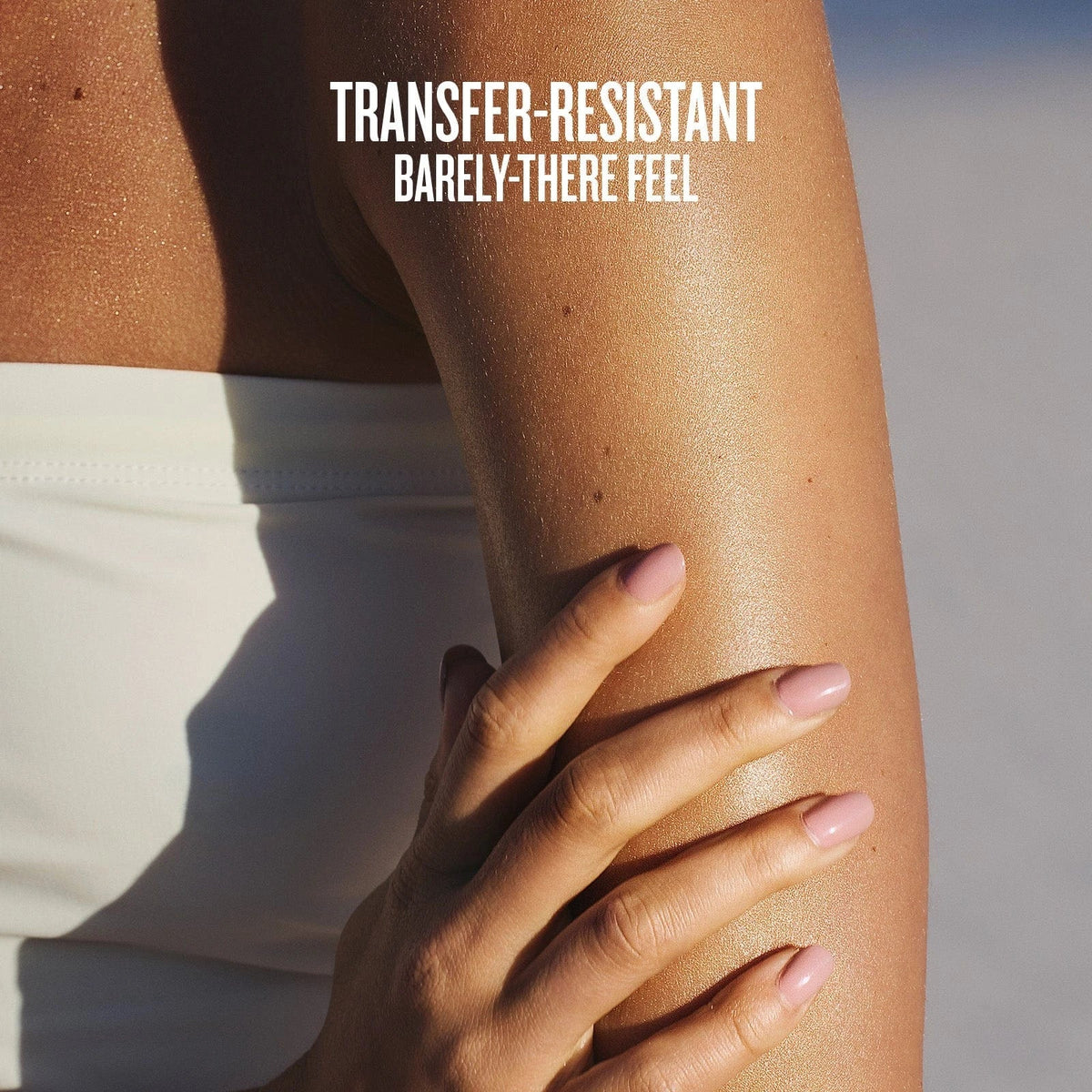 Text on image reads transfer-resistant barely-there feel. This is an image of a close up of model having the sol de janeiro glowmotions glow body oil on her arm and you can see how glowy and hydrated it makes her skin look